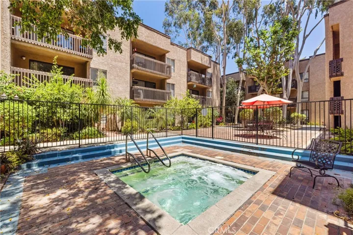 Sparkling community spa and pool surrounded by lush landscaping.
