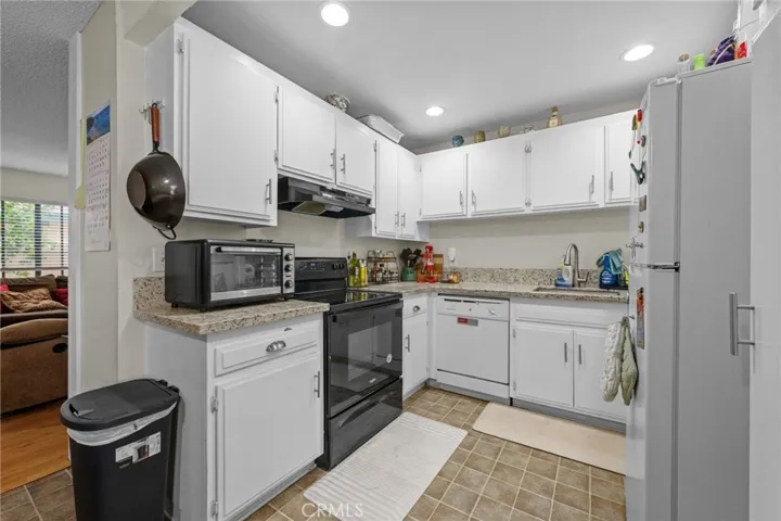 White kitchen with recessed lights and quartz counters.