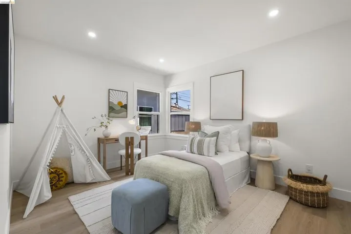 Bright bedroom featuring recessed lighting, dual windows, wood-finish flooring, and white baseboards