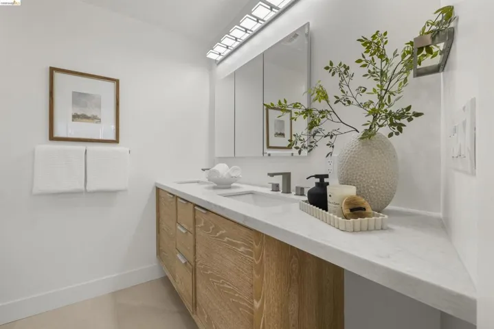 Dual vanity featuring light wood-finish cabinetry, integrated sinks, and polished chrome fixtures
