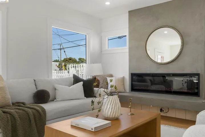 Living area featuring a contemporary fireplace with a sleek concrete surround, a large window, a smaller upper window, and light wood-finish flooring