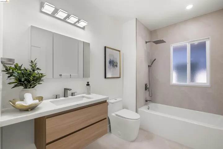 Contemporary bathroom featuring a floating wood-finish vanity with an integrated sink, a rectangular mirrored medicine cabinet, and a square wall-mounted light fixture