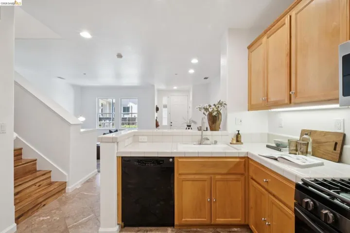Kitchen featuring wood-finish cabinetry, tile countertops, an integrated sink, and recessed lighting