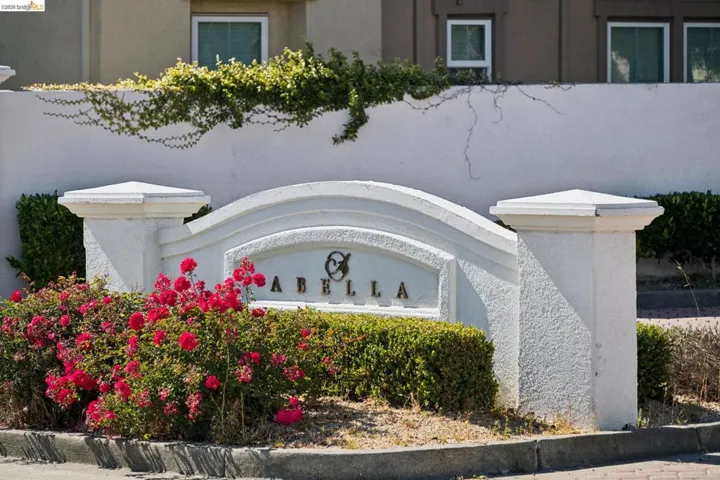 White stucco monument sign with arched detailing and gold-tone lettering
