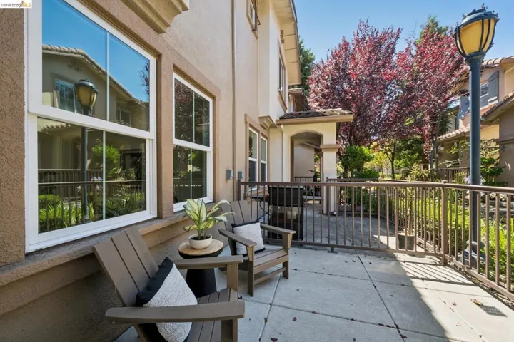 Outdoor patio featuring a concrete surface, metal railing, and stucco exterior