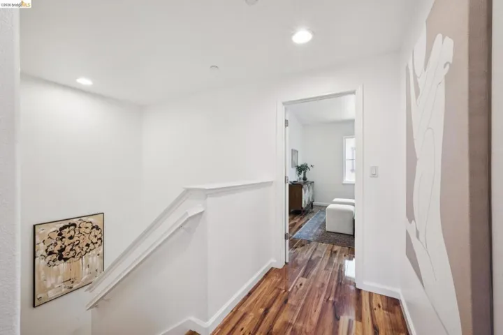 Hallway featuring wood-finish flooring, recessed lighting, and white baseboards