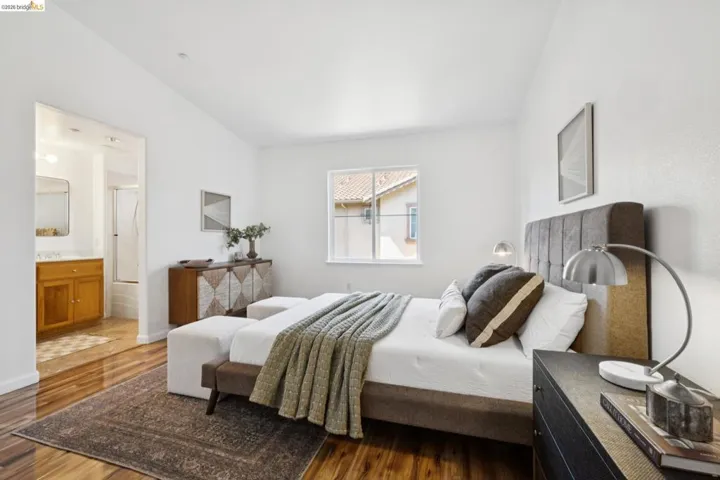 Spacious room featuring vaulted ceilings, wood-finish flooring, and a window with natural light