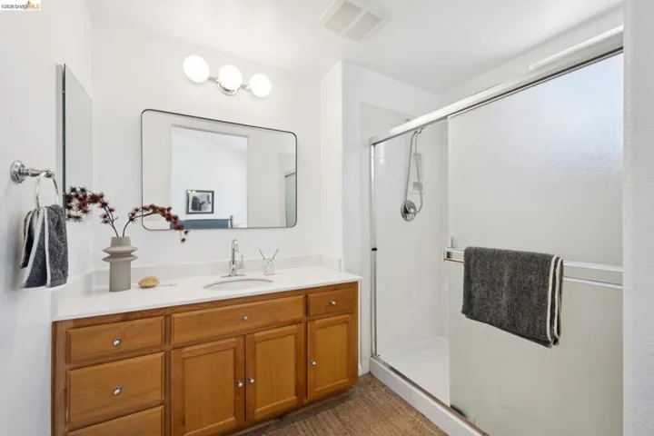 Bathroom featuring a wood vanity with a white countertop and undermount sink, a chrome faucet, and a rectangular mirror with a three-bulb light fixture