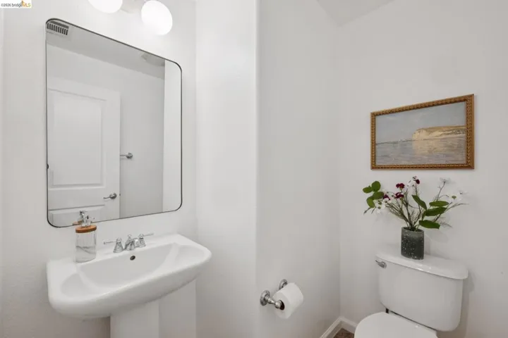 Pedestal sink with chrome faucet, framed rectangular mirror, and two spherical vanity lights
