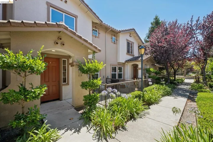 Multi-level exterior with stucco finish and tile roof, featuring an arched entryway, transom window, and prominent house numbers
