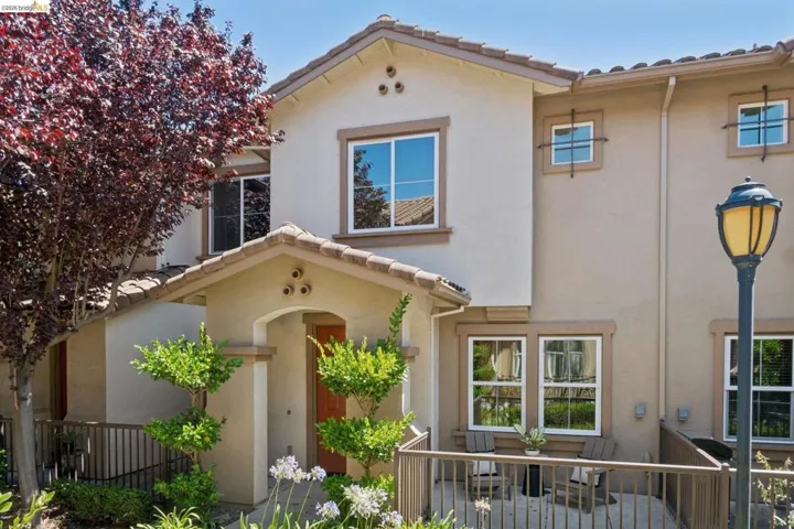 Stucco-finish exterior featuring a tile roof and arched entry