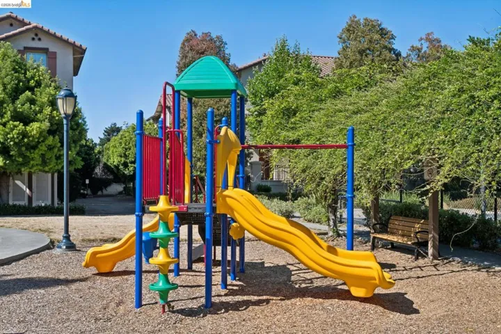 Community playground featuring a multi-level structure with two slides, climbing elements, and a bench