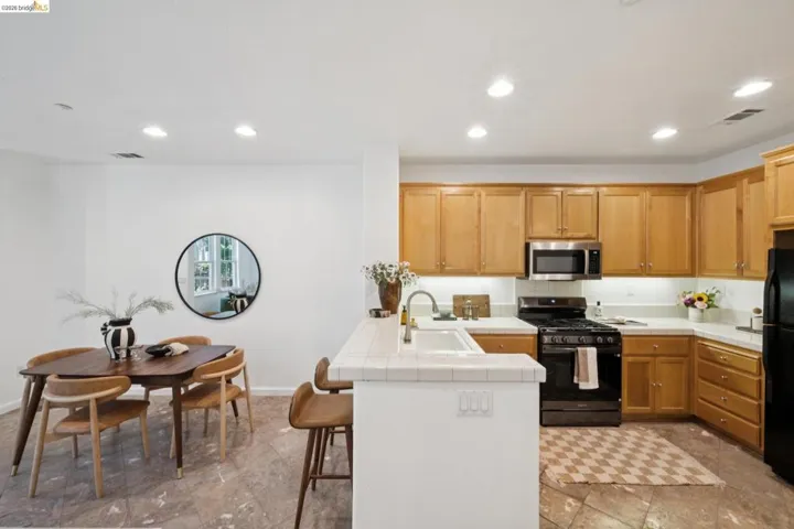 Kitchen featuring honey-toned cabinetry, light countertops, and a black appliance suite