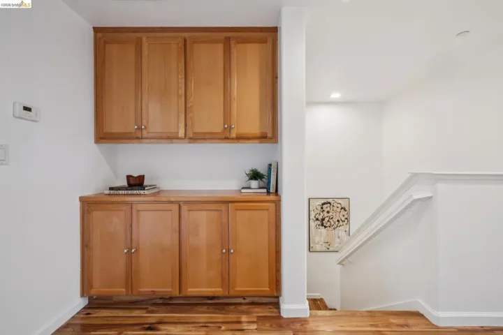 Built-in cabinetry with wood-finish doors and hardware, recessed lighting, and wood-finish flooring