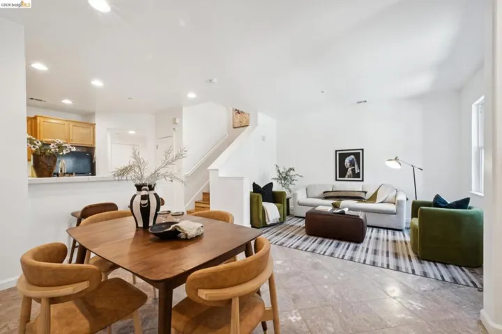 Spacious open-concept living area featuring light-toned flooring, recessed lighting, and a white color palette