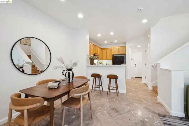Open concept living area featuring light-toned flooring, recessed lighting, and a kitchen pass-through with breakfast bar seating