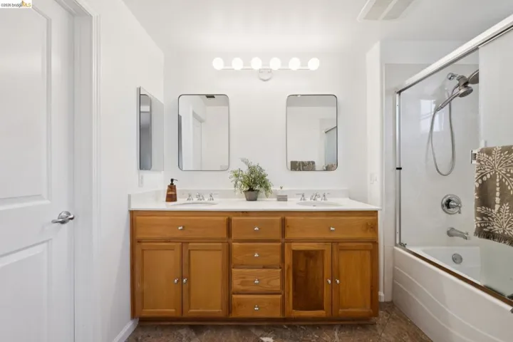 Double vanity featuring light wood-finish cabinetry and white countertops