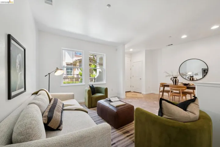 Open-concept living area with wood-finish flooring, recessed lighting, and white trim windows