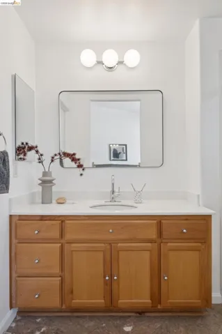Bathroom vanity featuring light-toned wood cabinetry with chrome hardware, an integrated sink, and a white countertop