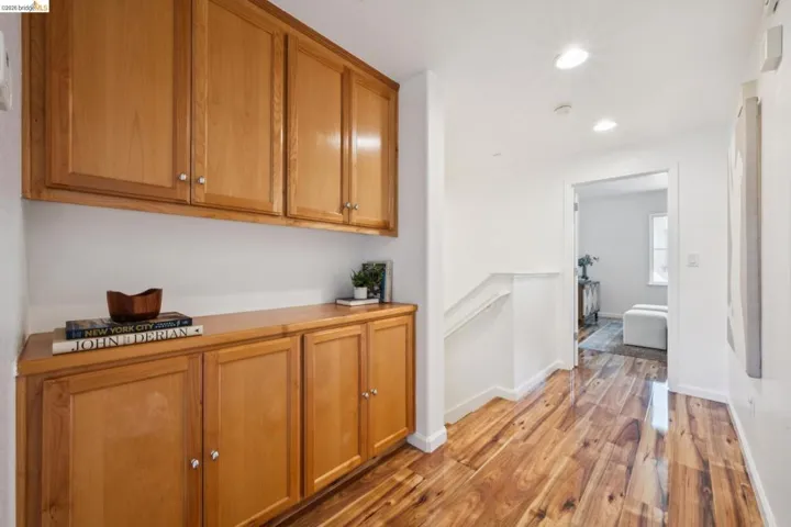 Hallway with extensive wood-finish built-in cabinetry, wood-finish flooring, recessed lighting, and a white stair railing