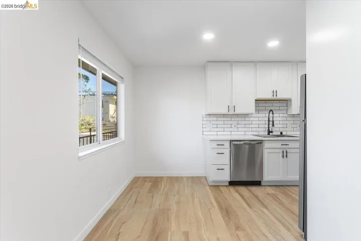 Kitchen with white cabinetry, stainless steel dishwasher, decorative backsplash, light wood-style floors, and recessed lighting