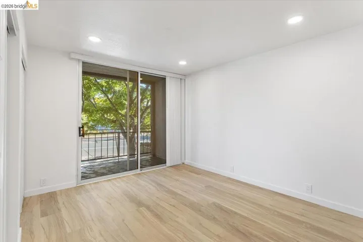 Empty room with a wall of windows, light wood-type flooring, and recessed lighting
