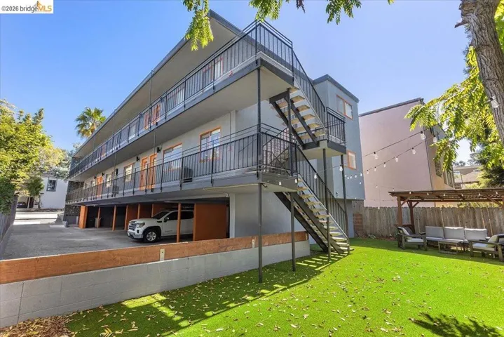 Back of house with stucco siding, stairs, a lawn, an outdoor living space, and a deck