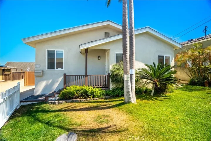 Front yard view showcasing the grassy lawn, palm trees, and welcoming outdoor setting.