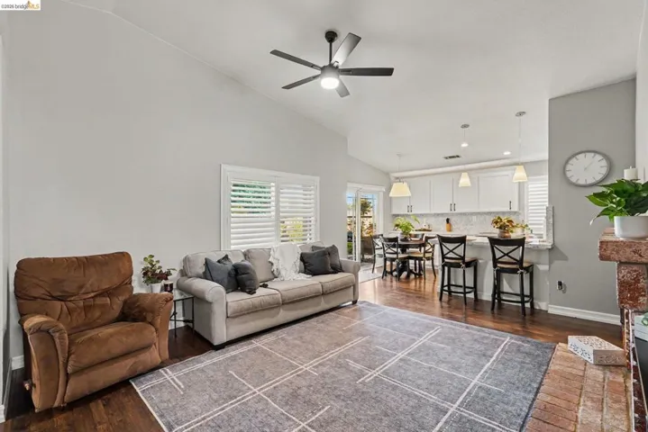 Vaulted ceilings complement the open-concept living space, featuring wood-finish flooring and a ceiling fan
