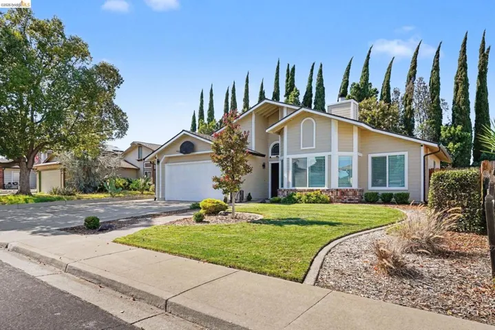 Two-story residence featuring a two-car garage, manicured lawn, and mature landscaping