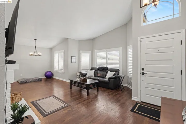 Entryway and living area featuring high vaulted ceilings, wood-finish flooring, and white plantation shutters