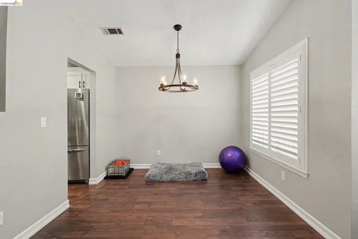 Room featuring rich wood-finish flooring, light gray wall paint, and white baseboards