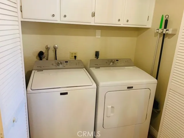 Laundry area/closet with full size washer and dryer and storage cabinets