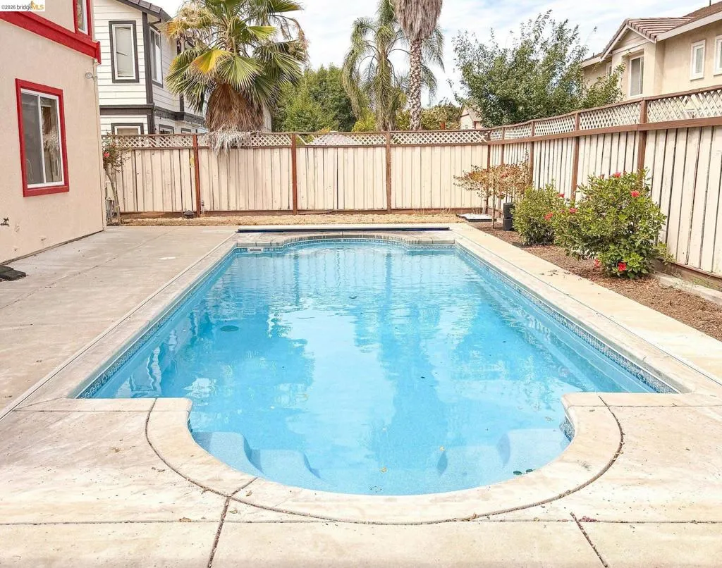 Rectangular in-ground pool featuring integrated steps and a surrounding concrete patio