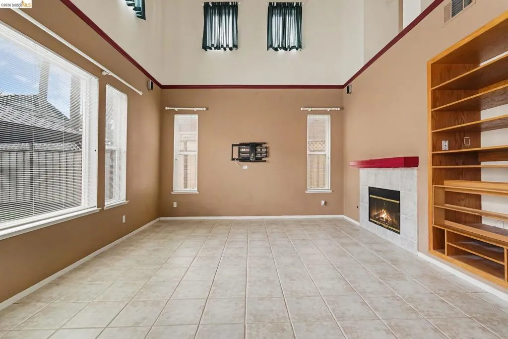 Spacious room featuring high vaulted ceilings and a built-in fireplace with a red mantel
