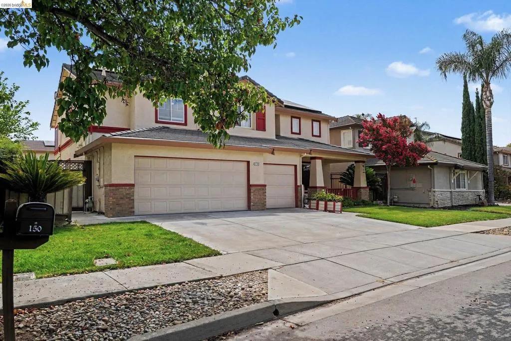 Two-story residence featuring a two-car garage, concrete driveway, and front lawn