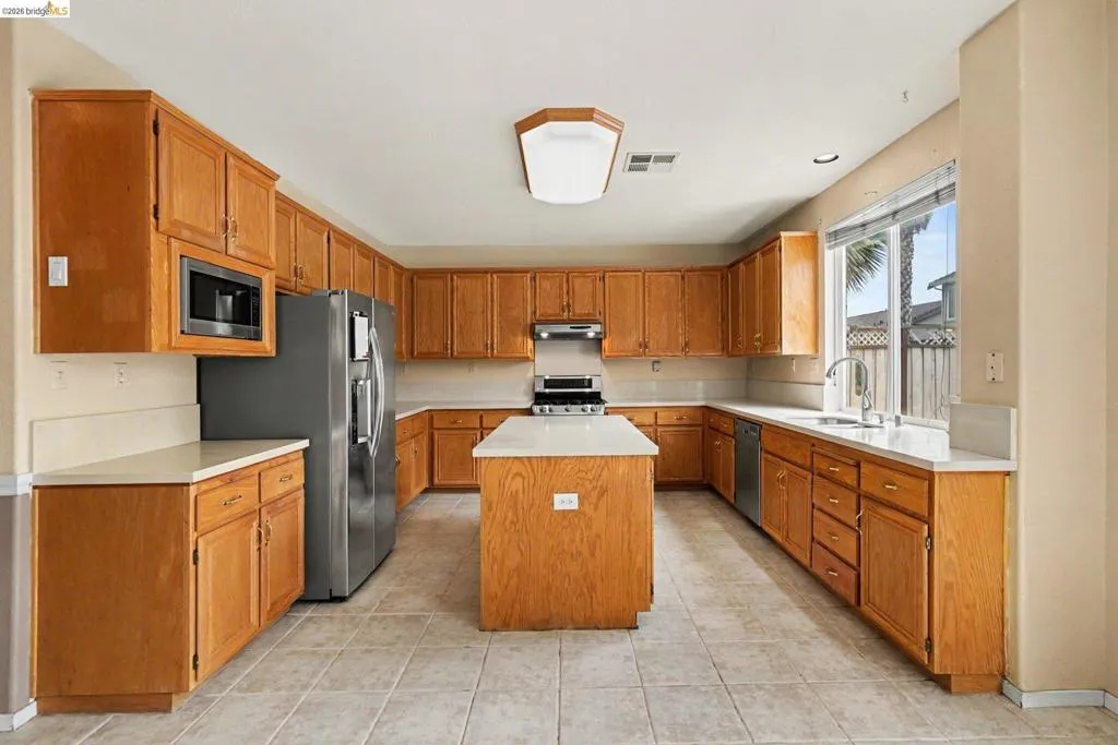 Kitchen featuring a central island, light wood-finish cabinetry, light countertops, and tile flooring