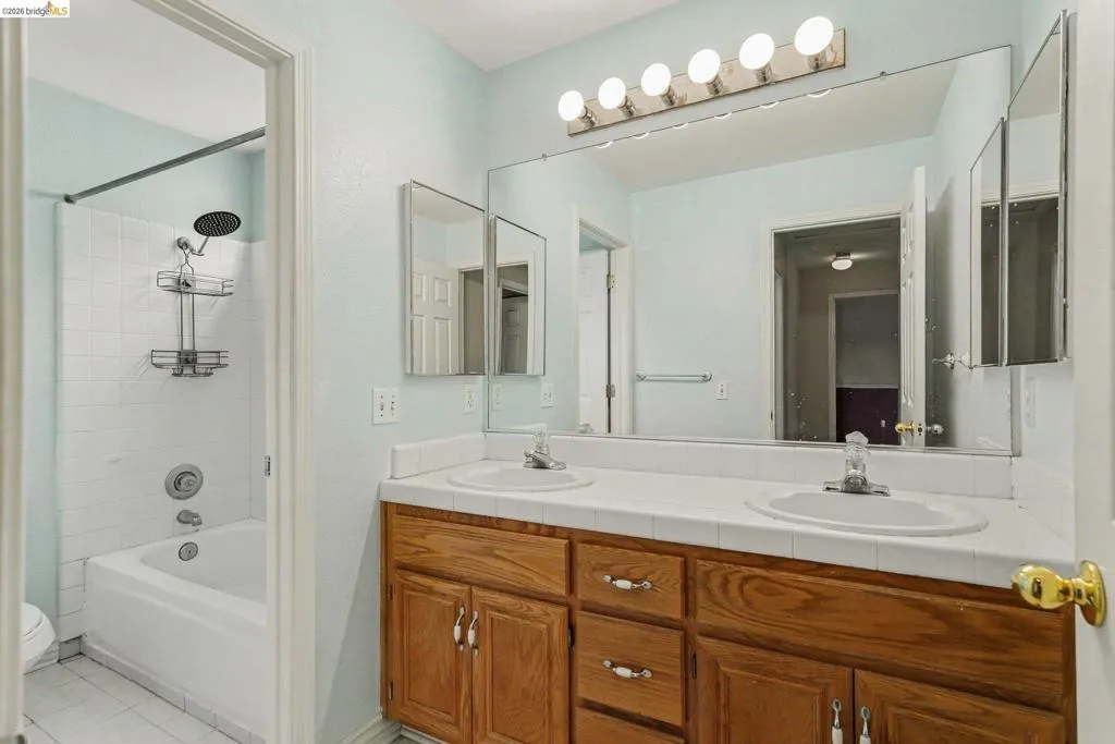 Double vanity with wood-finish cabinetry and white tile countertop