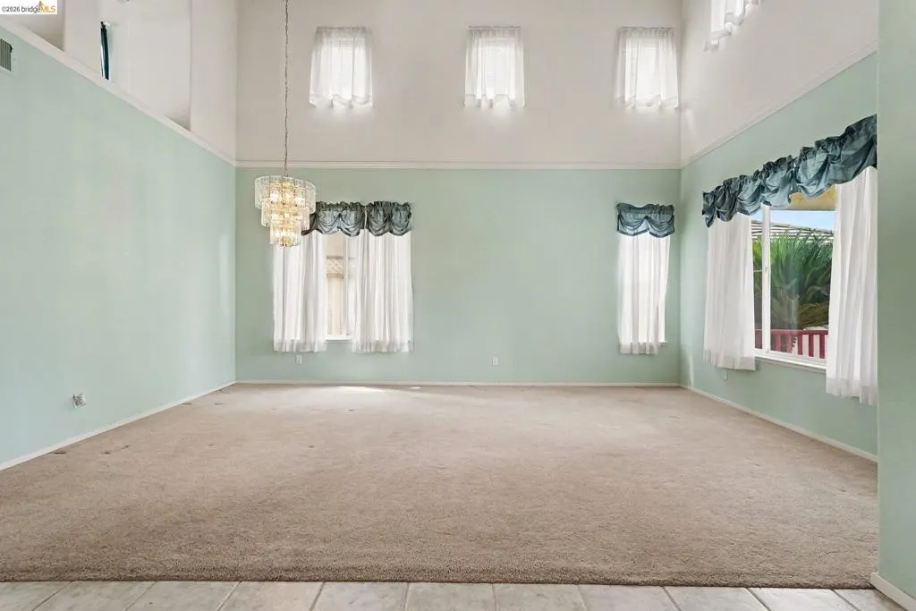 Spacious interior with neutral carpeting and a tiered chandelier