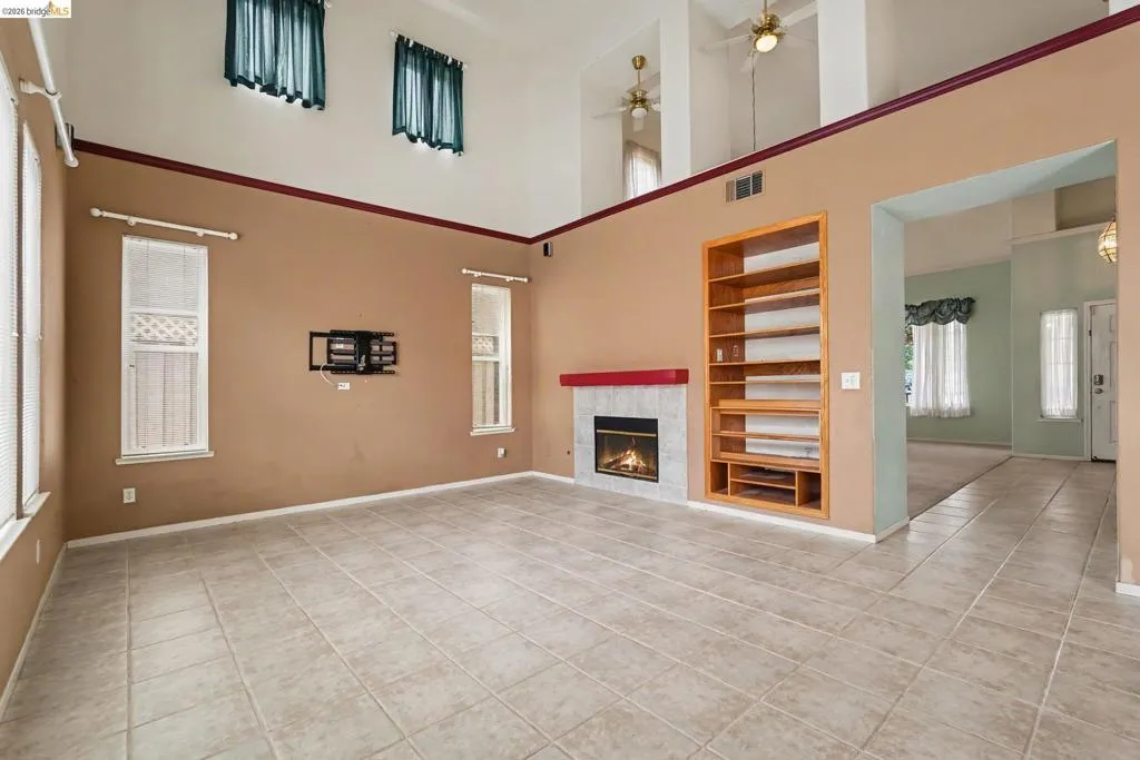Spacious living area featuring high ceilings, tile flooring, and a fireplace with a red mantel