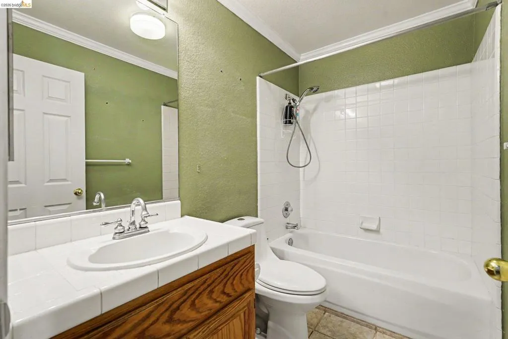 Bathroom featuring a vanity with wood-finish cabinetry, tile countertop, and integrated sink