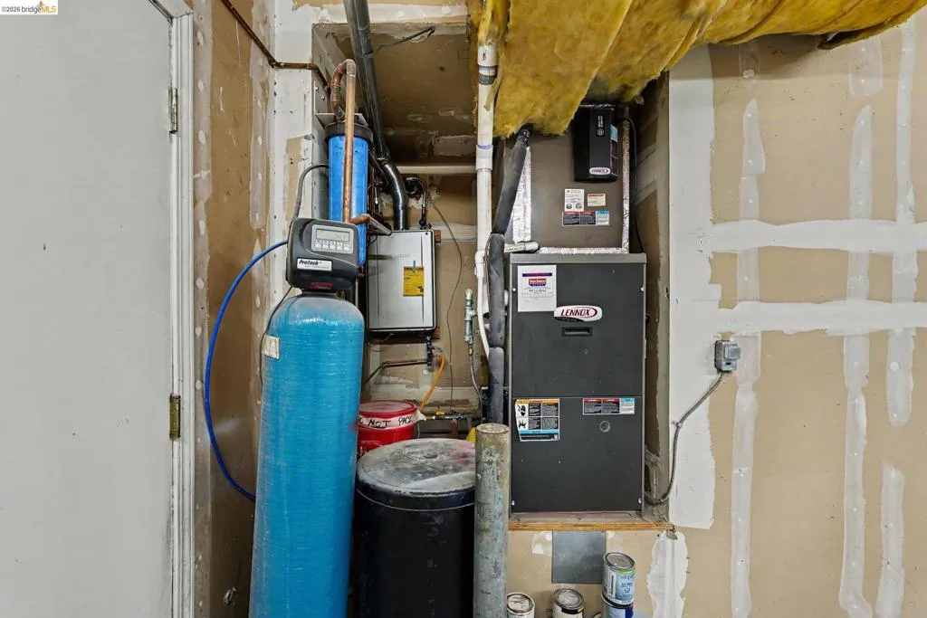 Dedicated utility area featuring a Lennox furnace, water conditioning system, and exposed copper piping