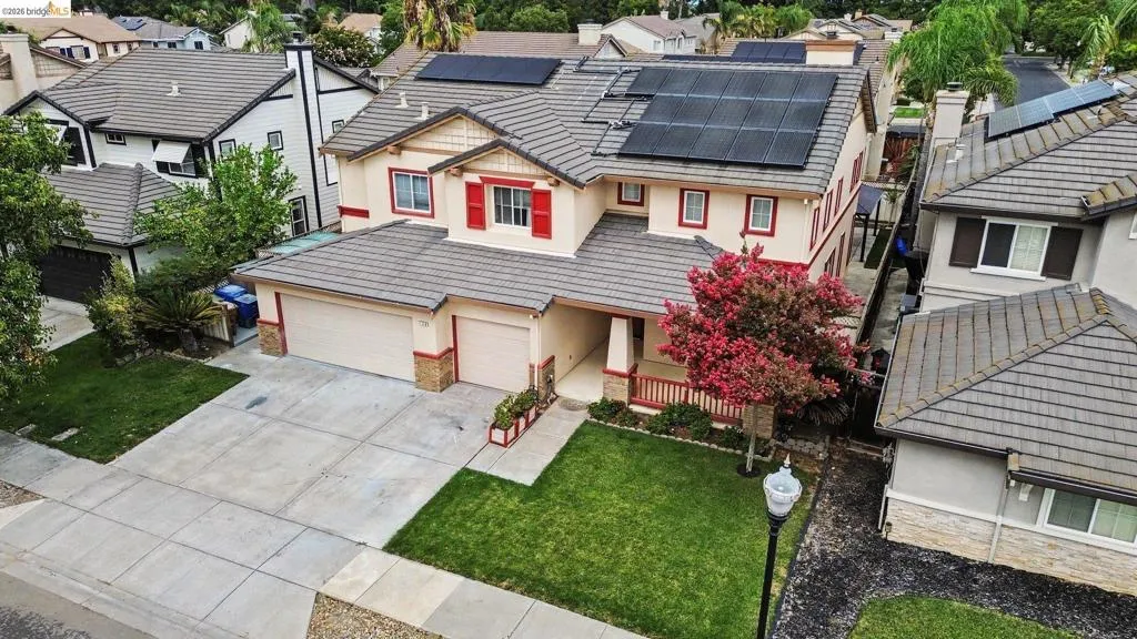 Two-story stucco residence featuring a tile roof, solar panels, an attached two-car garage, and a concrete driveway