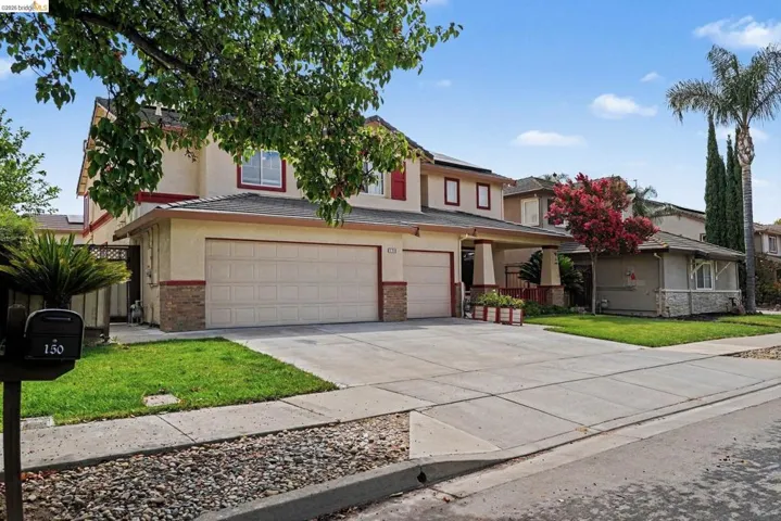 Two-story residence featuring a two-car garage, concrete driveway, and front lawn
