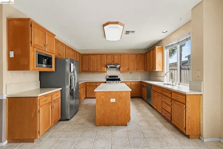 Kitchen featuring a central island, light wood-finish cabinetry, light countertops, and tile flooring