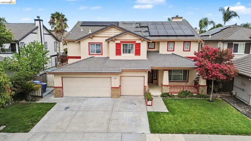 Two-story stucco exterior with red trim accents, a covered entry porch, and a two-car garage
