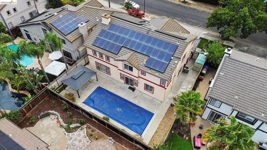 Two-story stucco residence featuring multiple solar panel arrays
