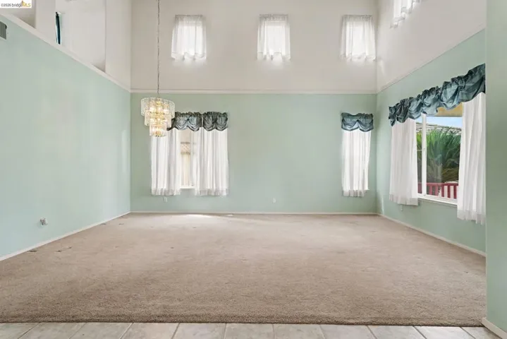 Spacious interior with neutral carpeting and a tiered chandelier