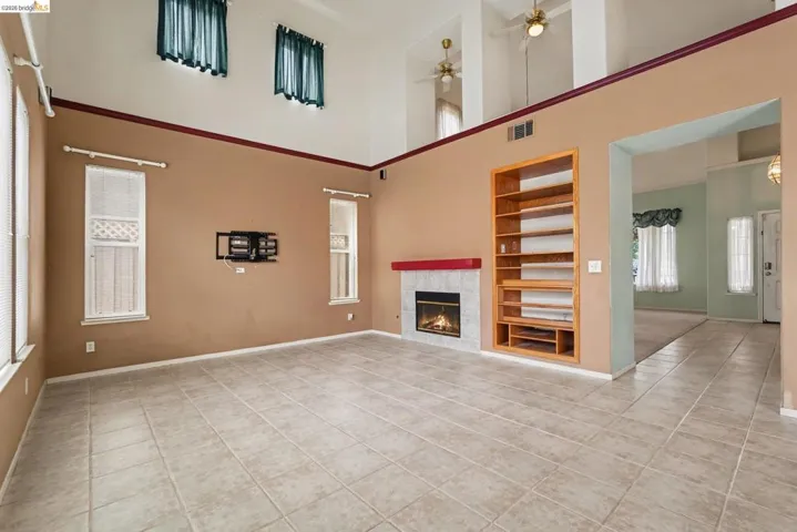 Spacious living area featuring high ceilings, tile flooring, and a fireplace with a red mantel
