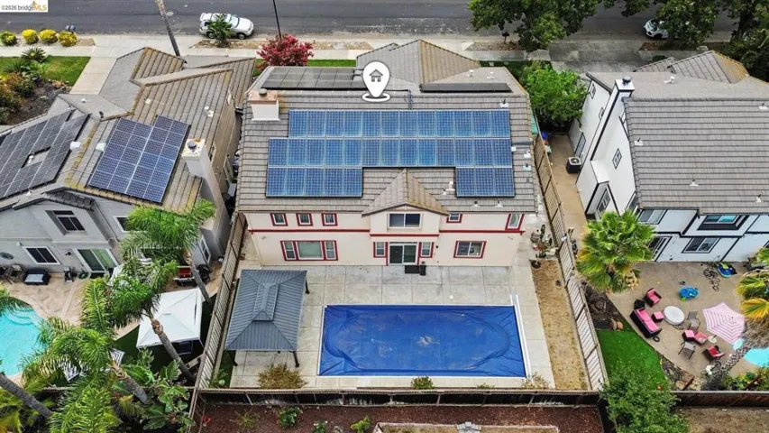 Expansive backyard featuring a covered pool, paved patio, and a dedicated covered outdoor structure